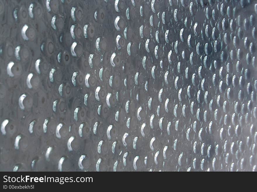 Water drops on a window with reflections from the sun.