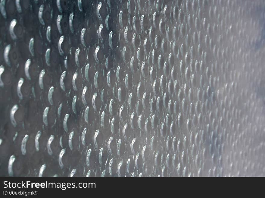 Water drops on a window with reflections from the sun.