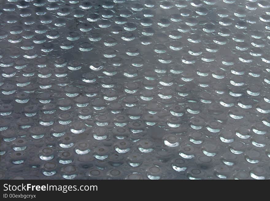 Water drops on a window with reflections from the sun.