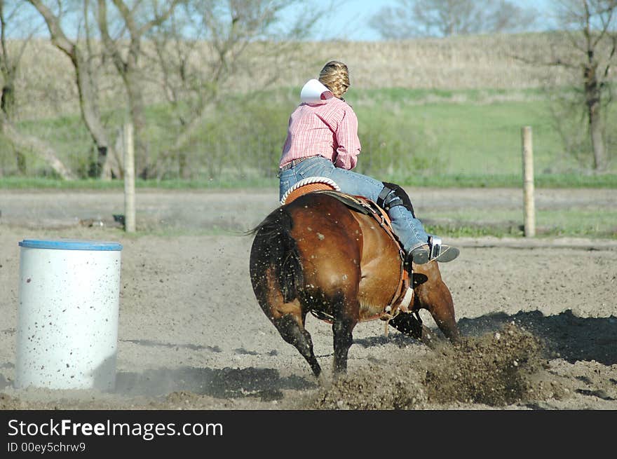 Woman on brwon horse making a sharp turn while barrel racing.