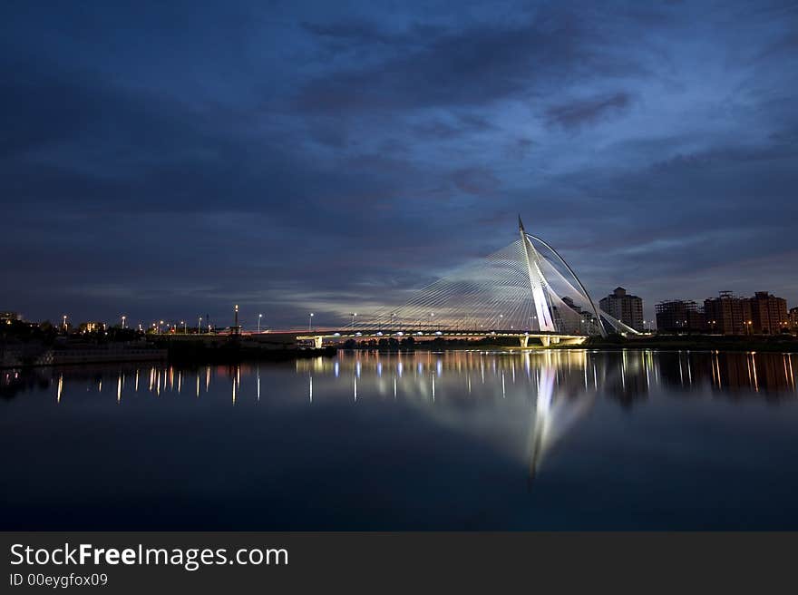 A bridge with a very unique design with a bench on the foreground