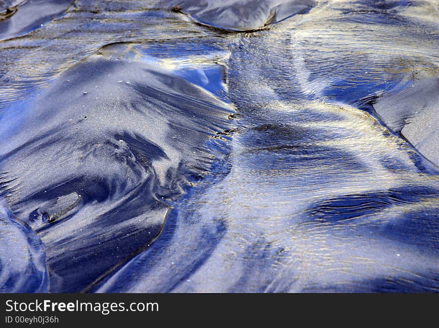 This is an image of sand on the beach that has been formed by wind, water, and natural elements. This is an image of sand on the beach that has been formed by wind, water, and natural elements.