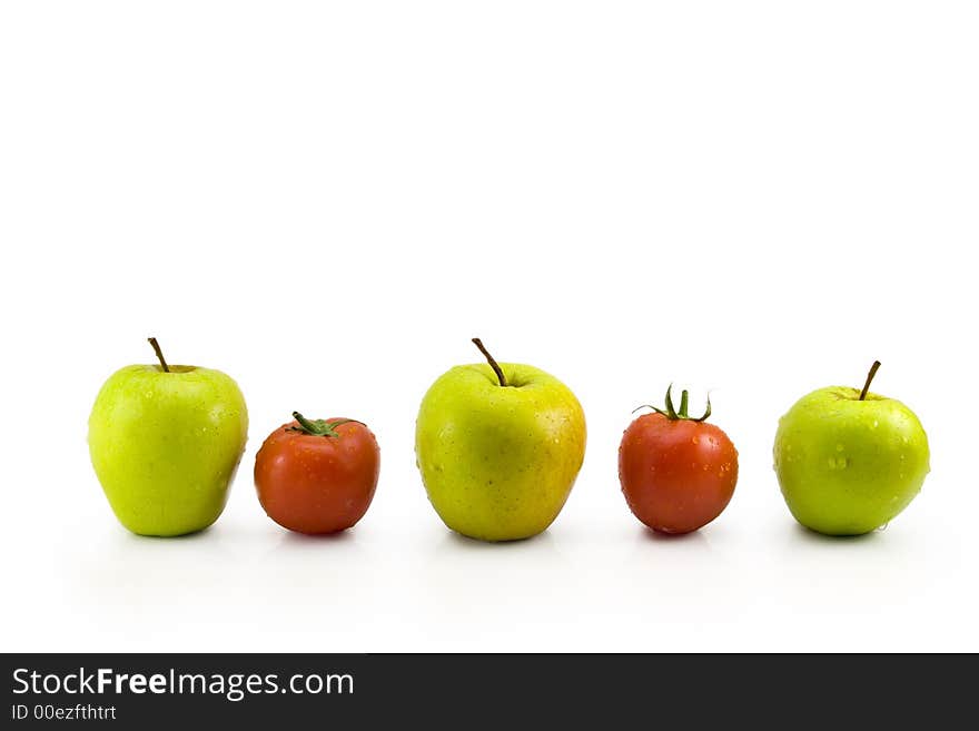 Fresh green apples and red tomatoes contrast in a row. Fresh green apples and red tomatoes contrast in a row