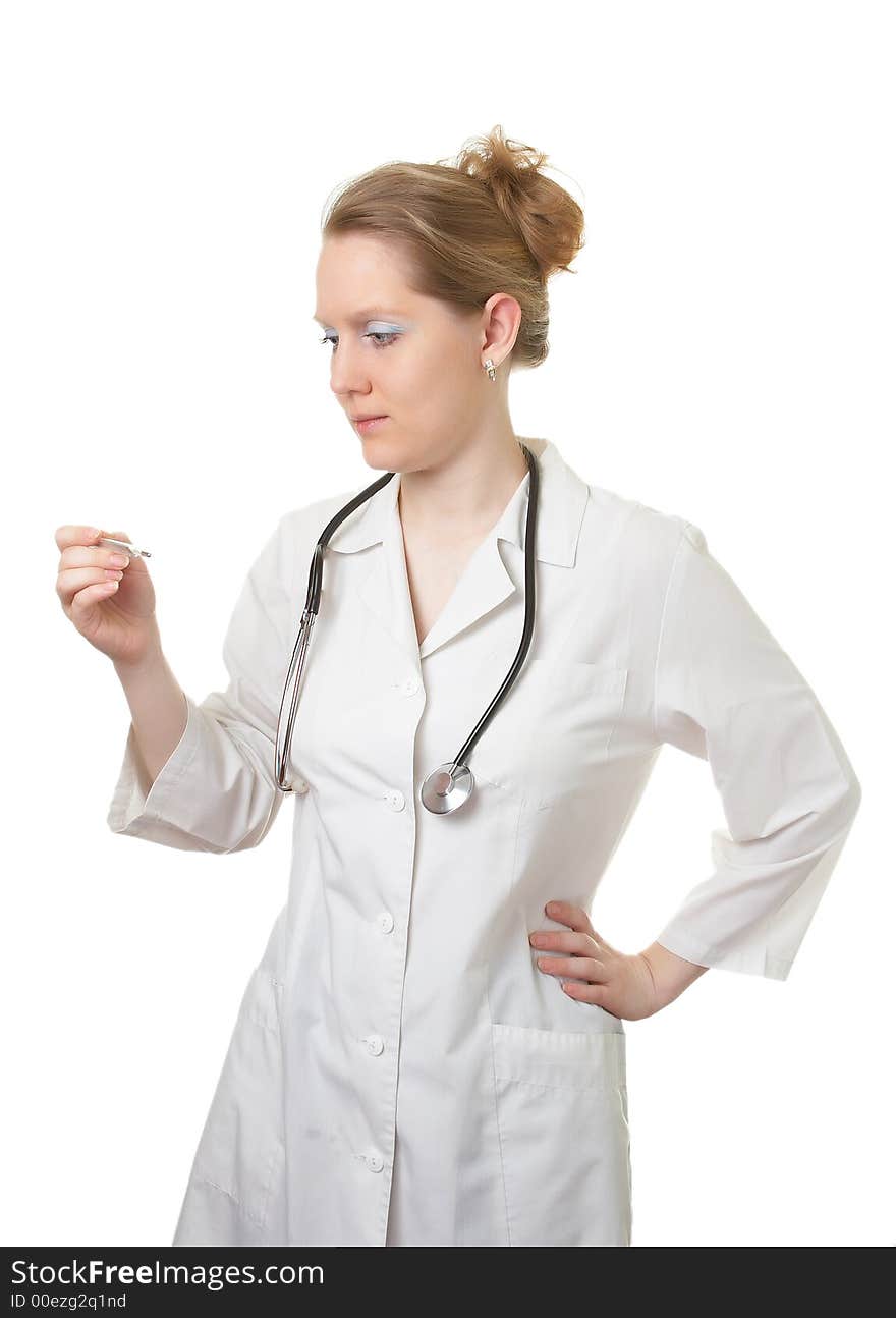 Woman the doctor in a white medical dressing gown with a stethoscope looks at a thermometer isolated on a white background. Woman the doctor in a white medical dressing gown with a stethoscope looks at a thermometer isolated on a white background