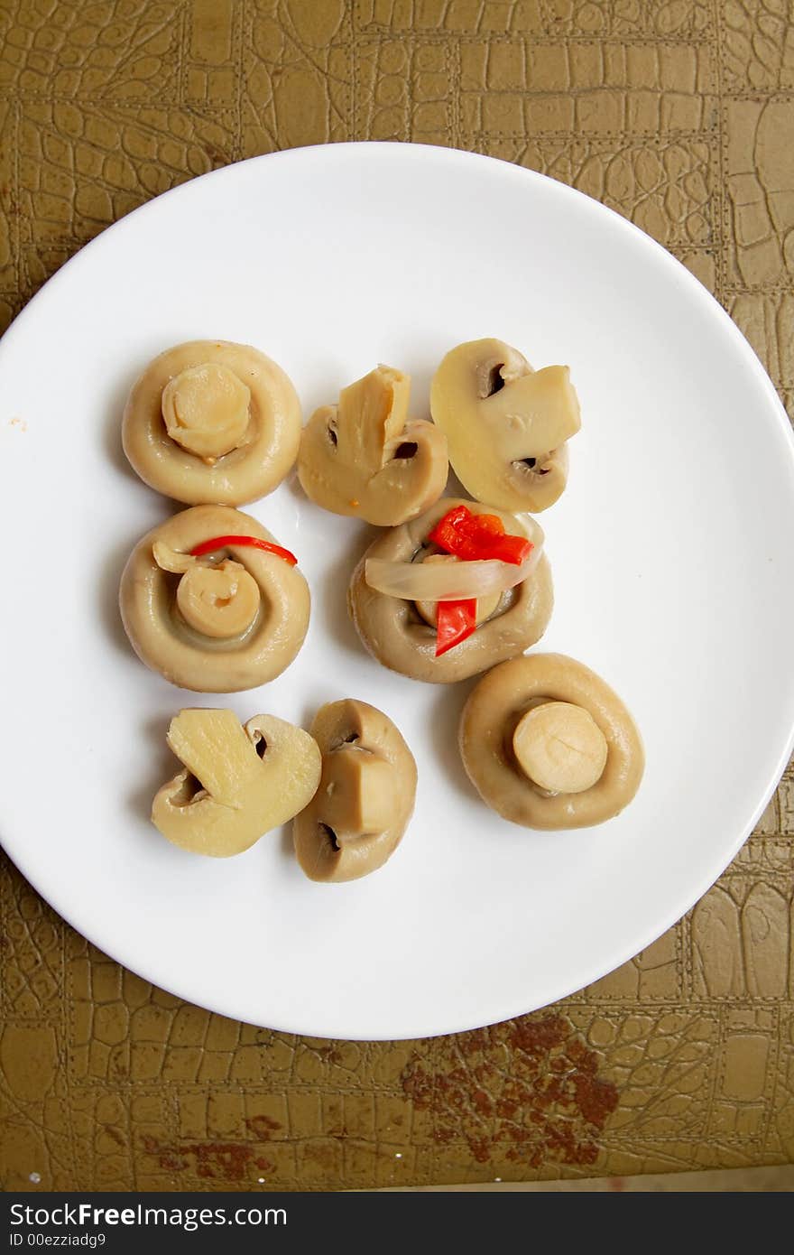 Eight marinaded mushrooms on a white plate