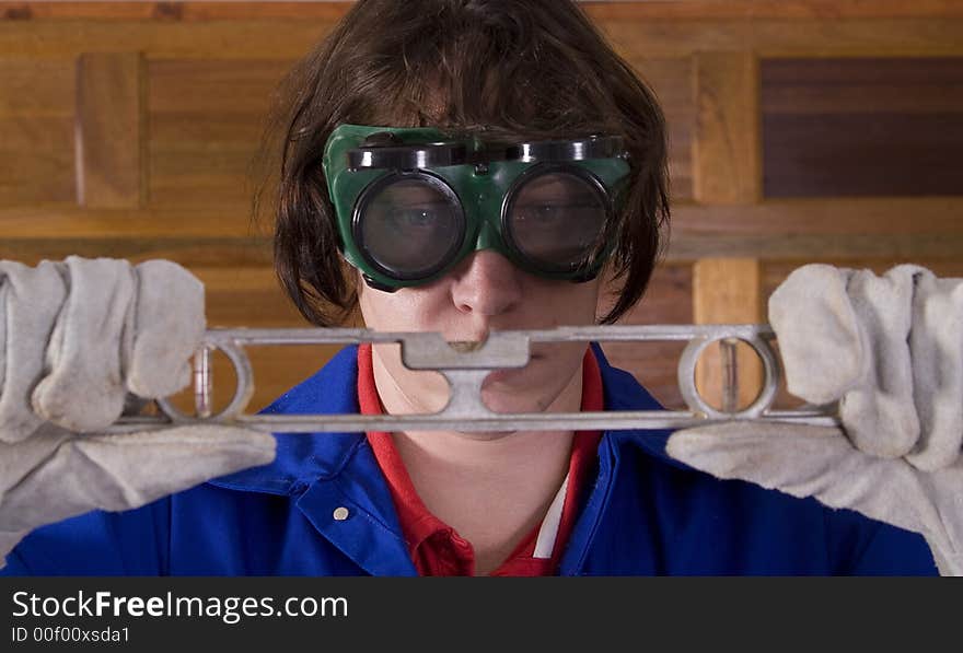 Handyman wearing goggles looking at leveller with gloves. Handyman wearing goggles looking at leveller with gloves