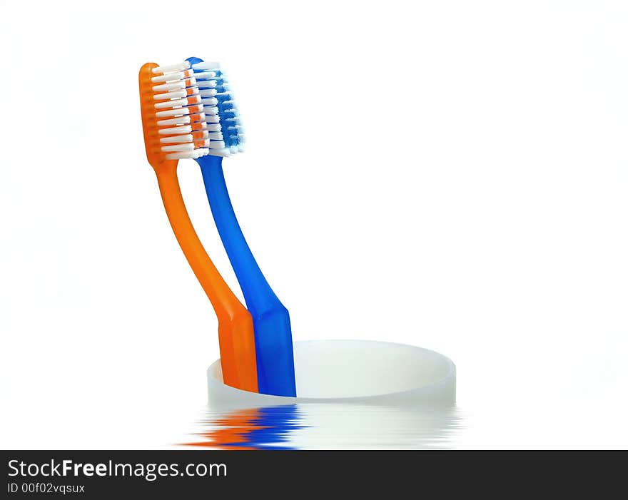 Tooth brushes on cup reflected in the water