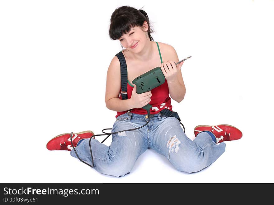 Smiling young girl holds a drill in her hand. sitting on the floor. Smiling young girl holds a drill in her hand. sitting on the floor.