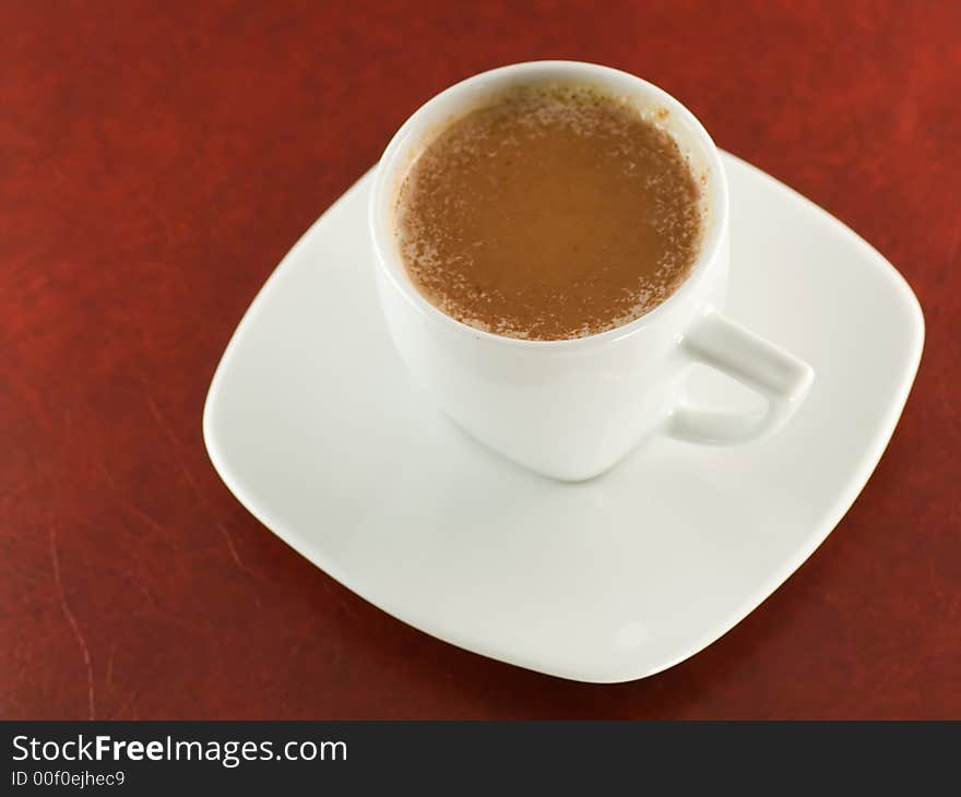 White cup of cappuccino on dark red background. White cup of cappuccino on dark red background