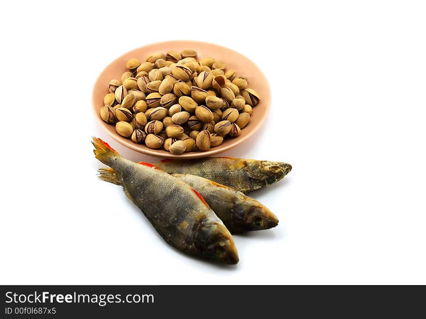 Beautiful the dried perch and pistachioes on a plate on a white background. Beautiful the dried perch and pistachioes on a plate on a white background