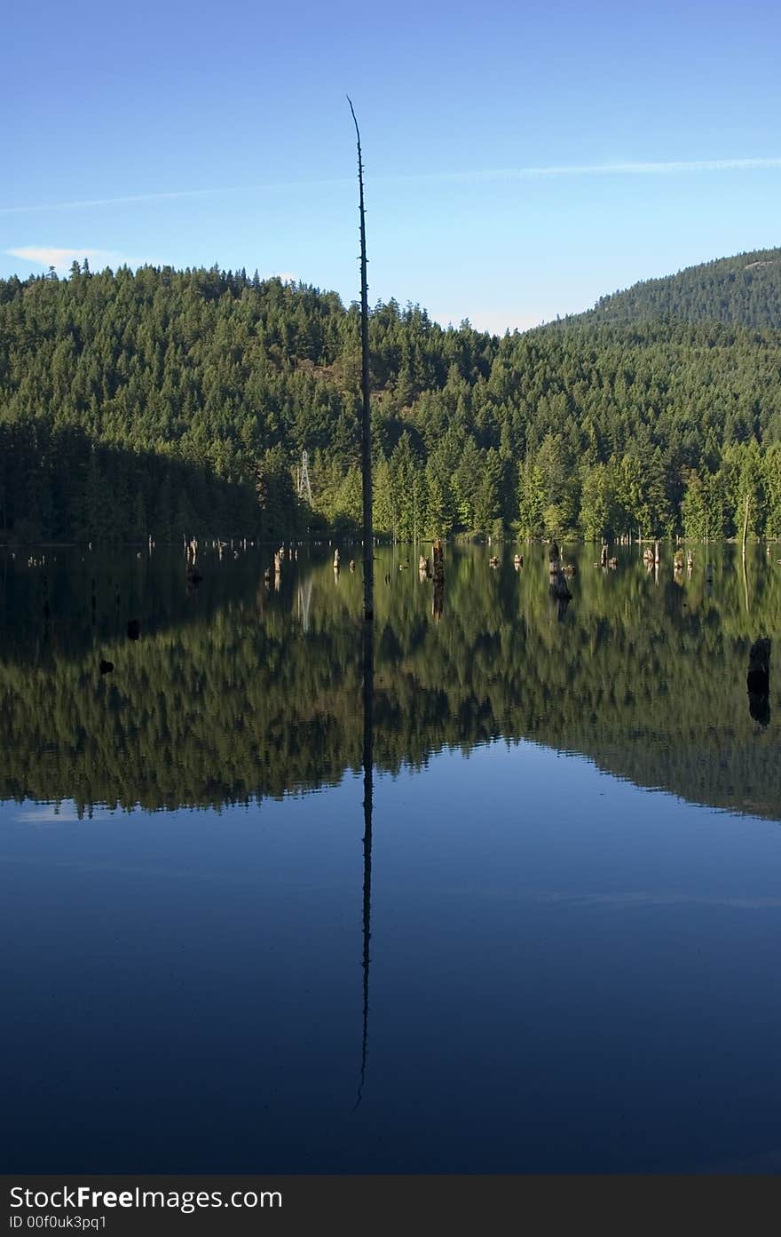 A small lake on vancouver island mirrors the sky on the water surface. A small lake on vancouver island mirrors the sky on the water surface.