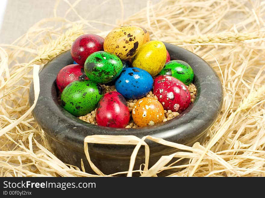 Colorful eggs in bowl in straw