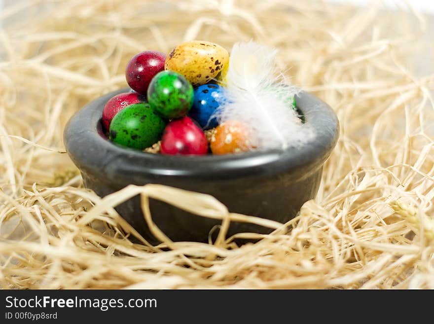 Colorful eggs in bowl in straw