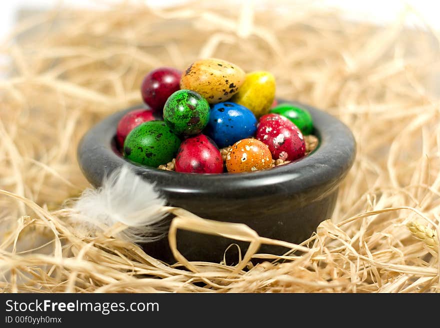 Colorful eggs in bowl in straw