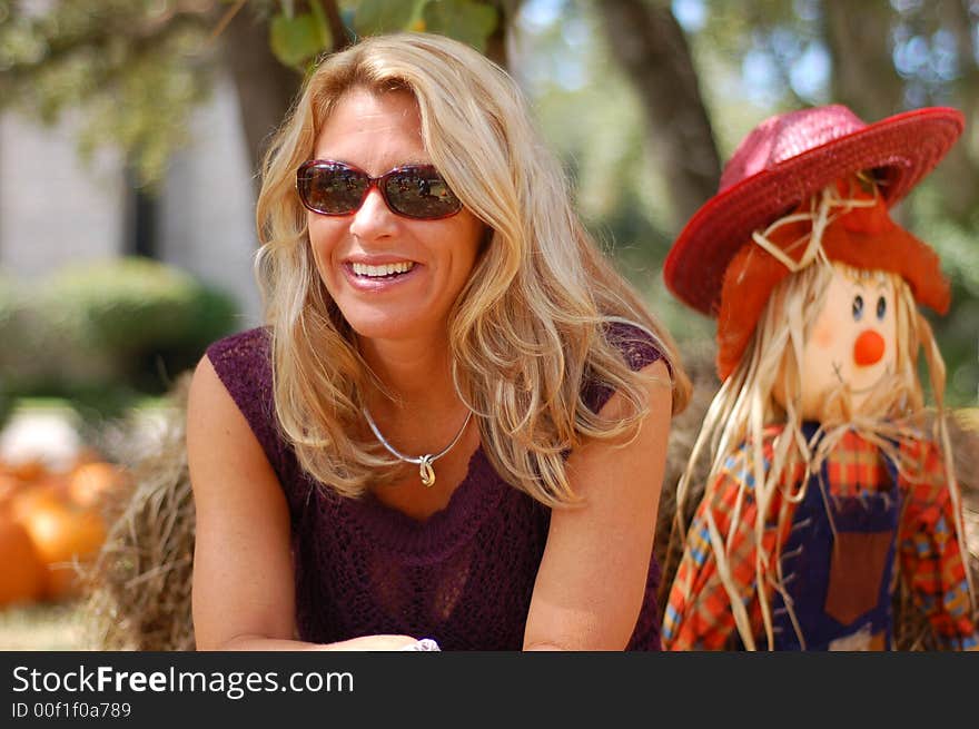 Beautiful woman posed near a scarecrow for classic fall portrait. Beautiful woman posed near a scarecrow for classic fall portrait