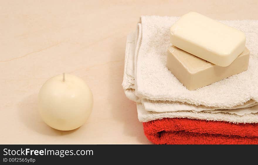 Red and white towels and honey soaps with candle in spa bathroom (spa concept )