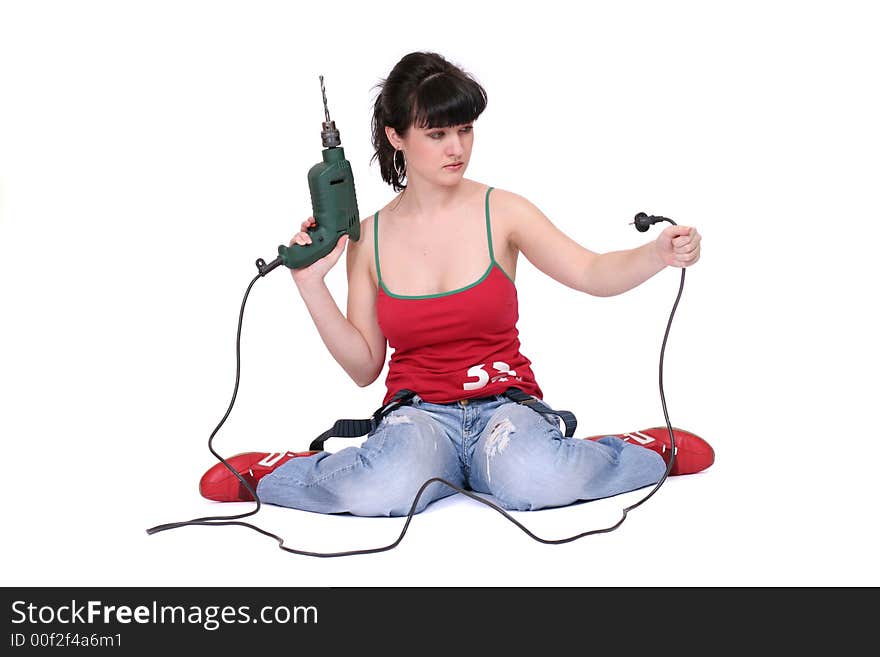 A woman sits and looks at a drill's flex with incomprehension. White background. A woman sits and looks at a drill's flex with incomprehension. White background