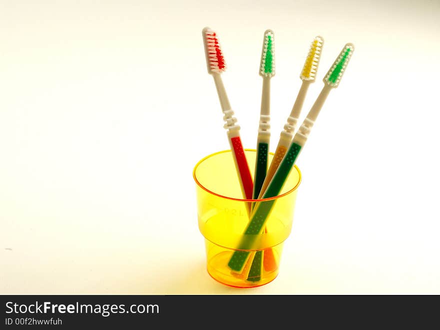 Four tooth-brushes in  plastic orange glass on  white background