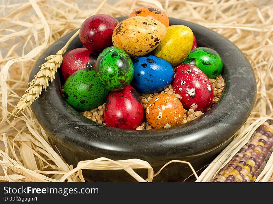 Colorful eggs in bowl in straw