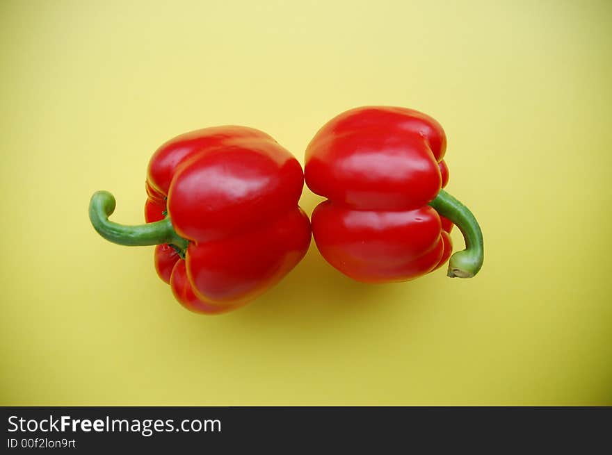 Two red peppers on yellow