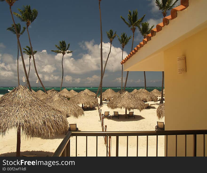 Hot sunny beach with grass sunshades shading lounge chairs. Hot sunny beach with grass sunshades shading lounge chairs.