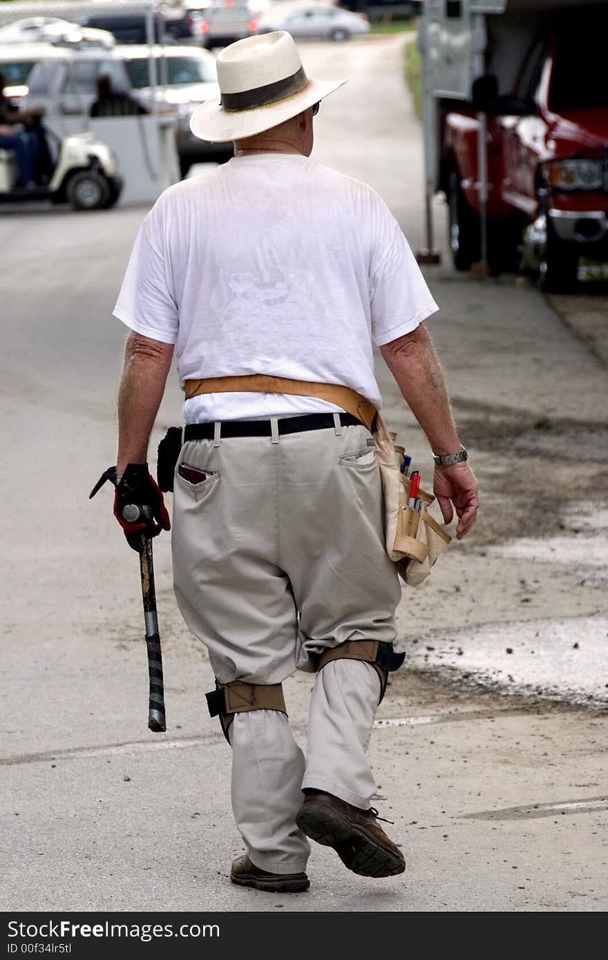 A House Framer is just finishing his day helping a number of volunteers build a house. He is wearing his tool belt with tools and a hammer in his left hand. A House Framer is just finishing his day helping a number of volunteers build a house. He is wearing his tool belt with tools and a hammer in his left hand