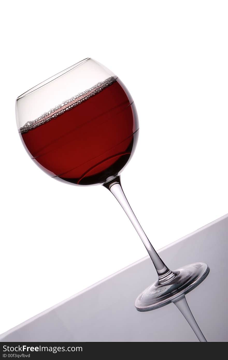 Glass of red wine shot against a white background with back lighting. Glass of red wine shot against a white background with back lighting.