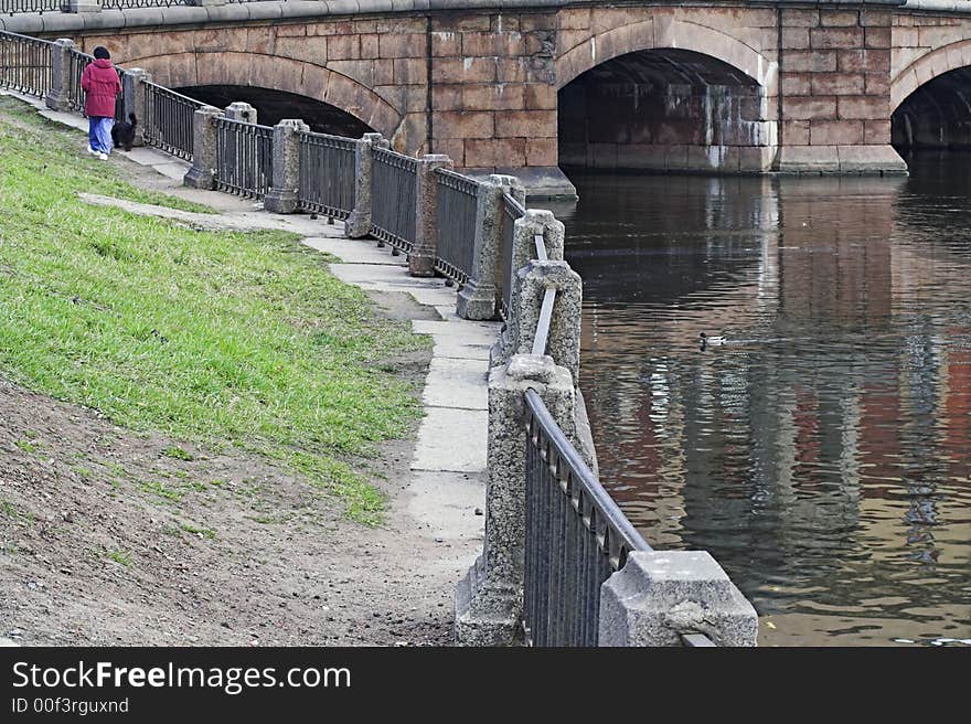 Woman walking her dog along river embankment