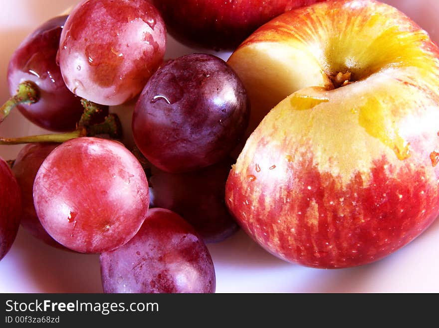 Fresh red grapes and cut apple with water drops on the plate. Fresh red grapes and cut apple with water drops on the plate