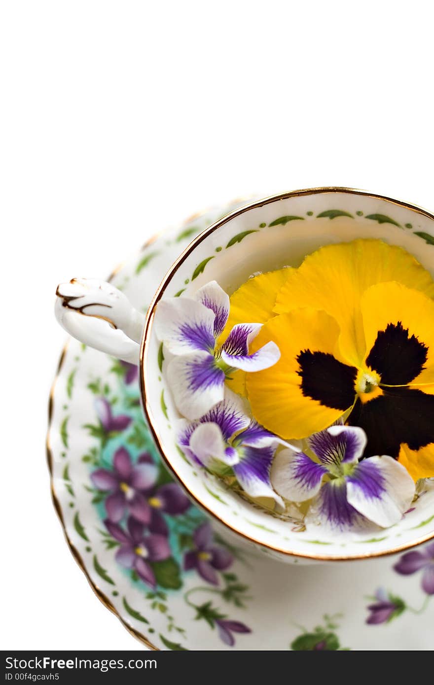 Teacup with pansies and violets on white background - shallow depth of field. Teacup with pansies and violets on white background - shallow depth of field.