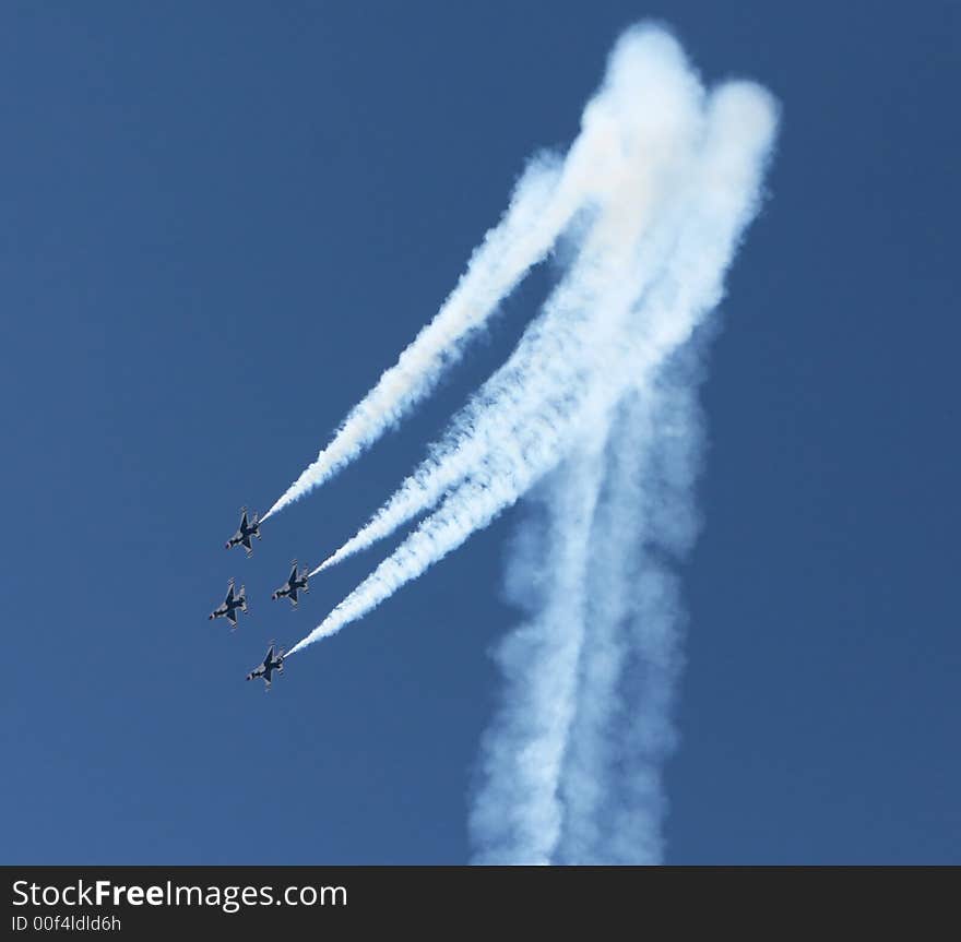 Four fighter jets flying in formation against a clear blue sky