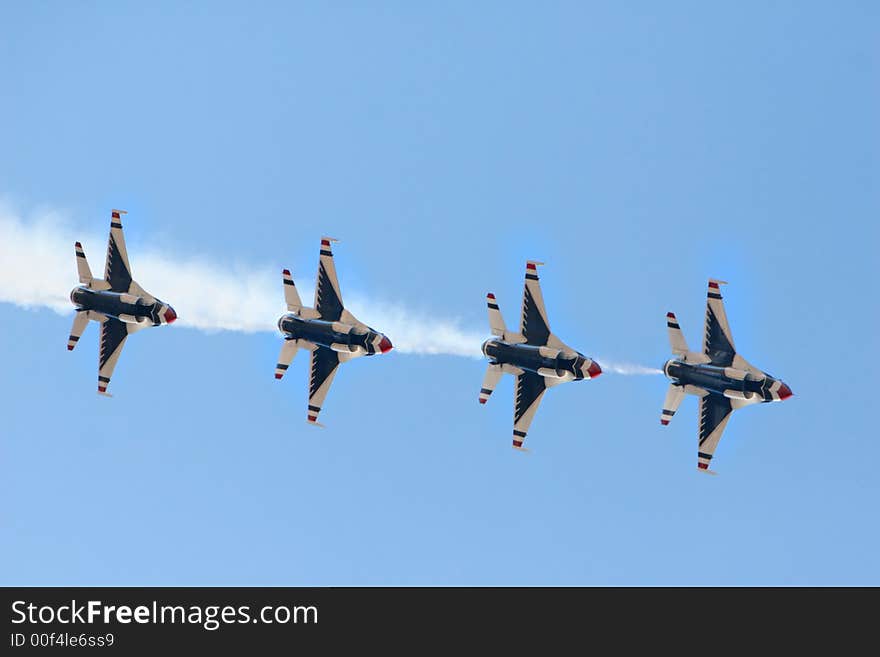 Four fighter jets flying in formation against a clear blue sky