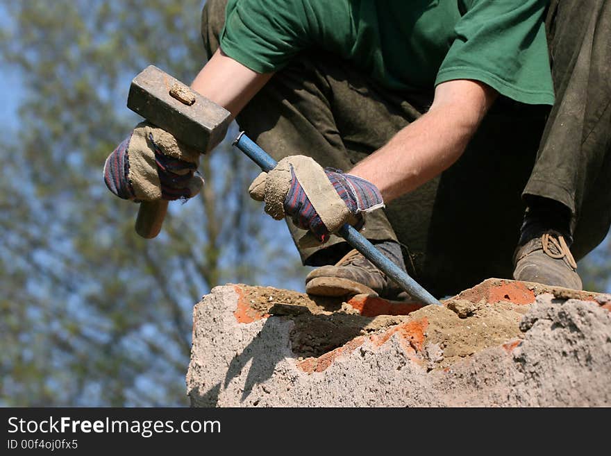 Worksman with hammer and chisel during demolition of wall