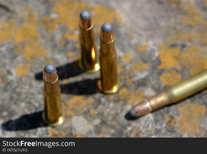 A small group of bullets sitting on a chunk of old sandstone.