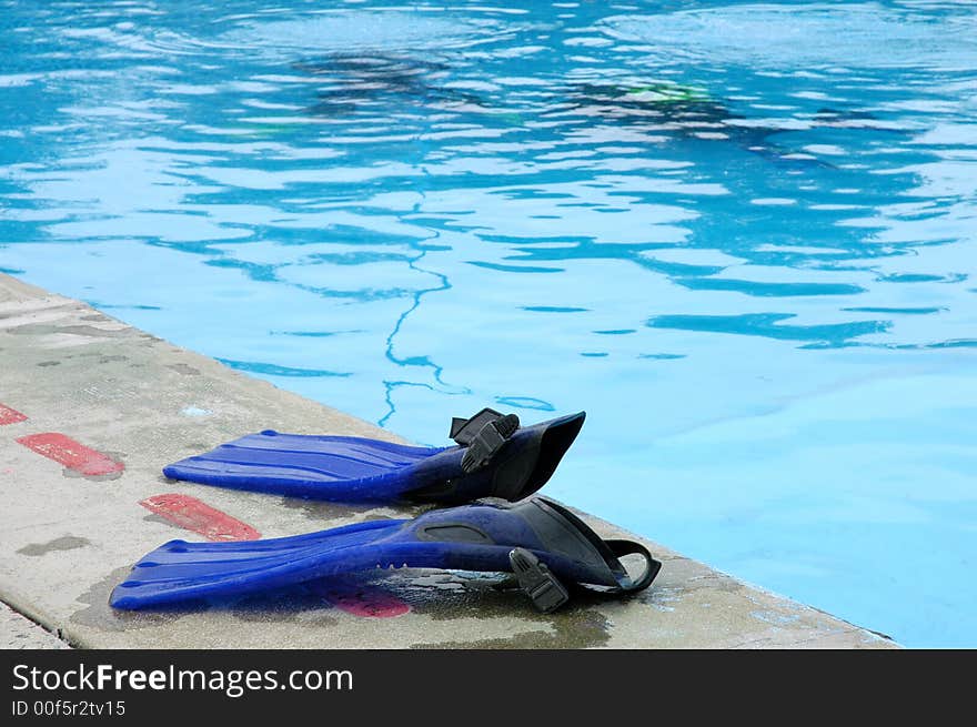 Two blue swim fins by the swimming pool