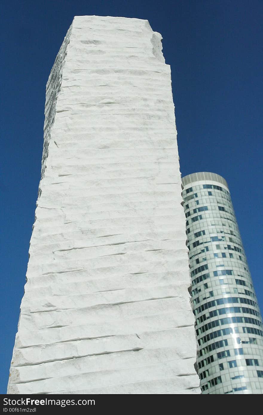 Stone monument in Paris, La Defence , with skyscraper in backgroud