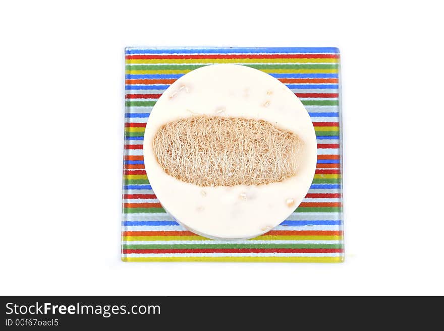 Vanilla soap and loofah on a colorful striped dish - isolated