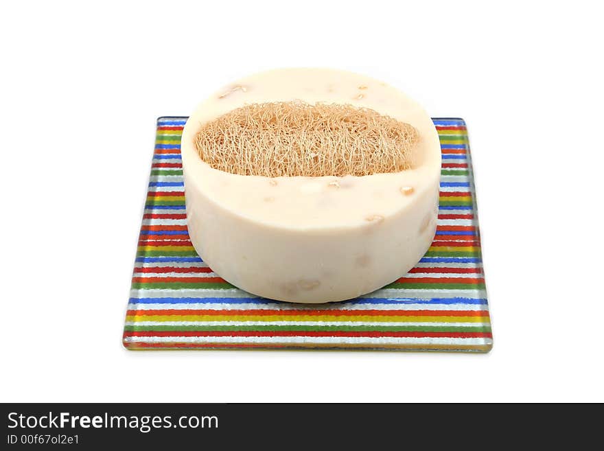 Vanilla soap and loofah on a colorful dish - isolated