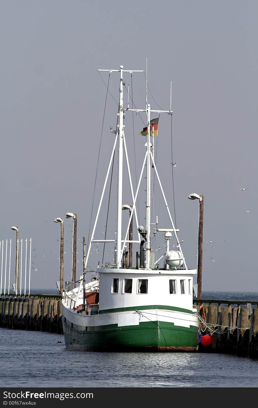 Green fishingboat at quay on blue sky. Green fishingboat at quay on blue sky