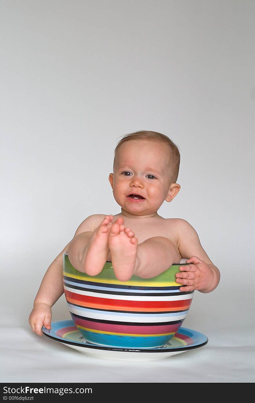 Image of an adorable baby sitting in a colorful, over-sized teacup. Image of an adorable baby sitting in a colorful, over-sized teacup