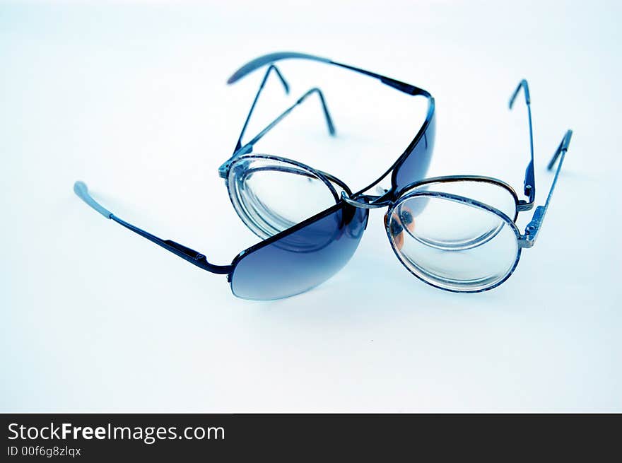 Three pair of eyeglasses, posed on a white, blue filtered background in a dynamic tension. Three pair of eyeglasses, posed on a white, blue filtered background in a dynamic tension.