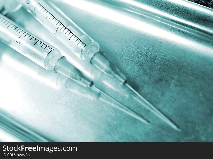 Two syringes on the stainless steel tray. Macro, special blue toned photo f/x