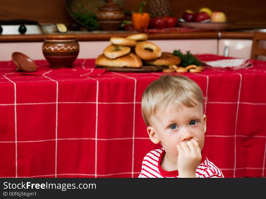 Little boy eating cracknel in the kitchen