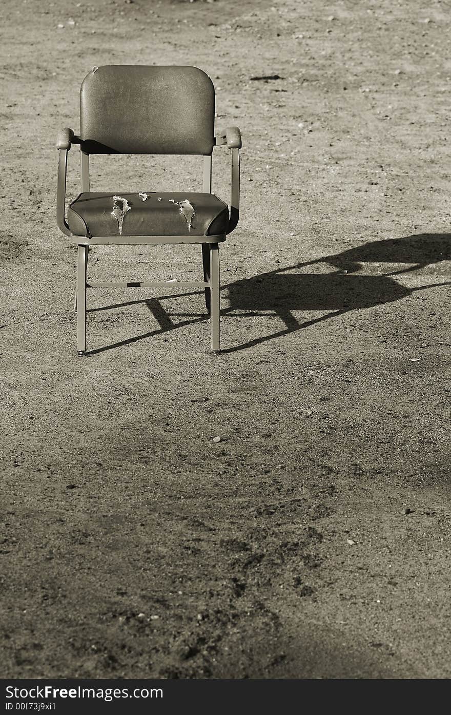 Toned old chair alone in dirt