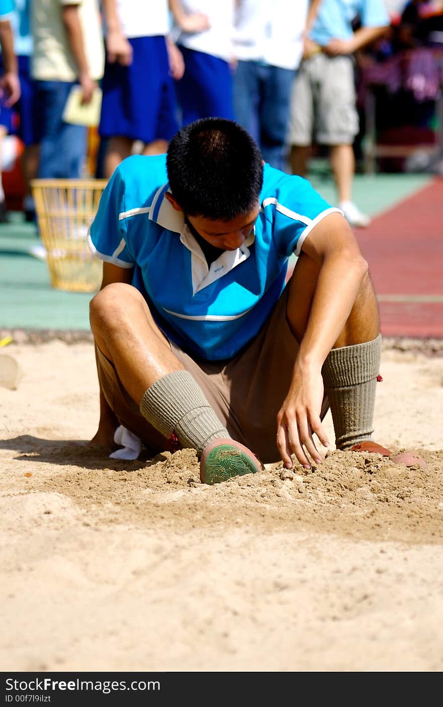 A Boy sitting on the sands field after long jump. A Boy sitting on the sands field after long jump.