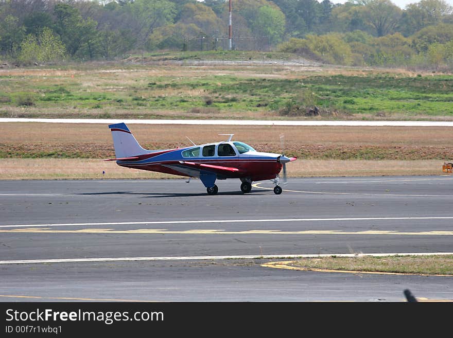 A small red and white plane landing at a small airport