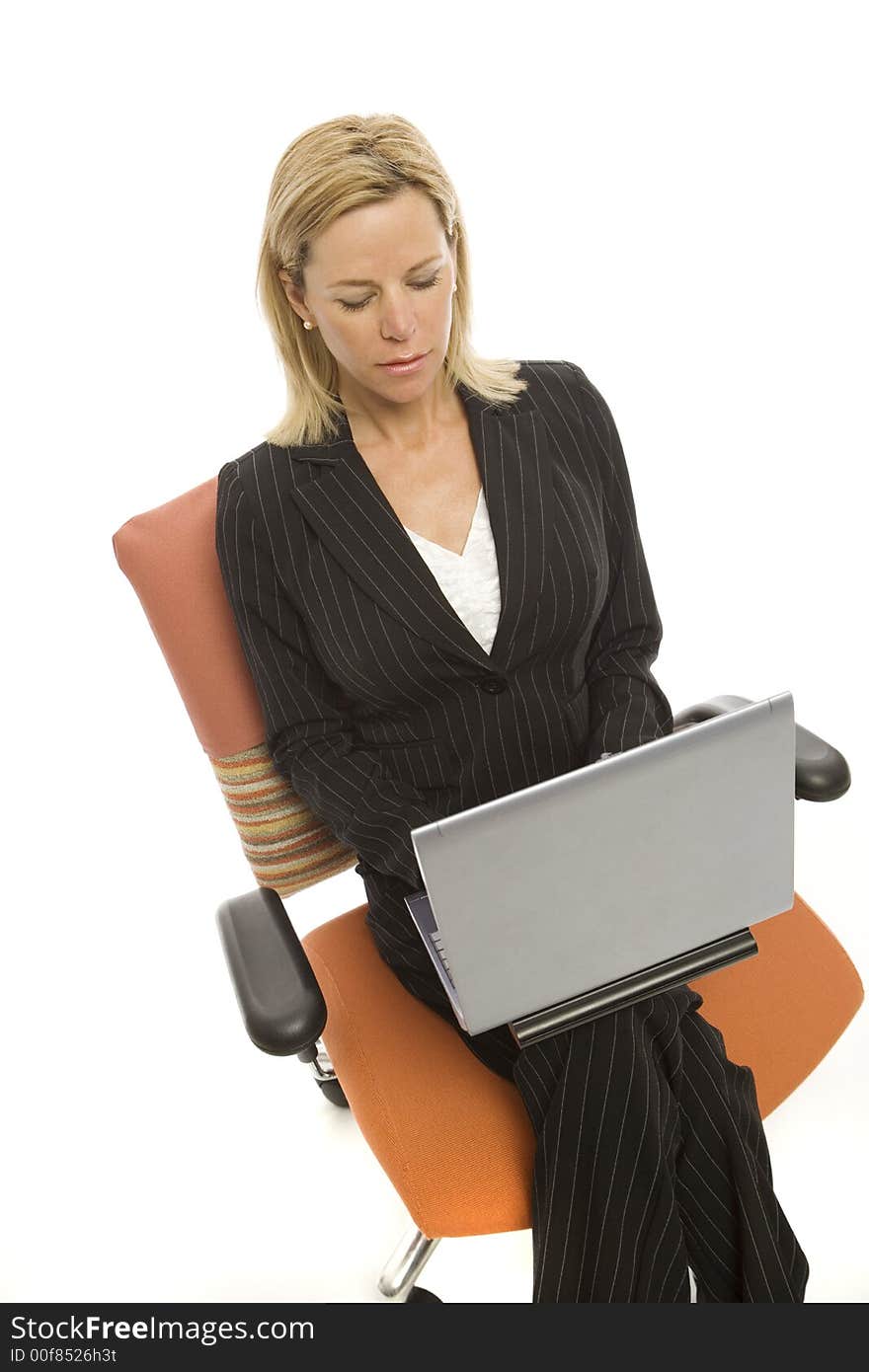 A businesswoman in a pinstripe suit sits relaxing in a chair with a laptop computer. A businesswoman in a pinstripe suit sits relaxing in a chair with a laptop computer