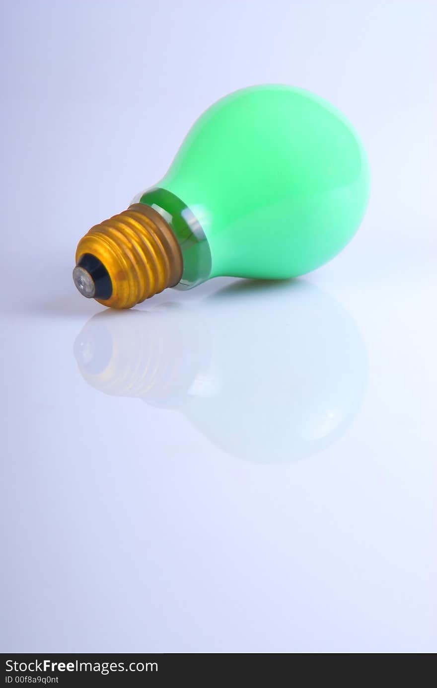 A green lightbulb over white with reflection