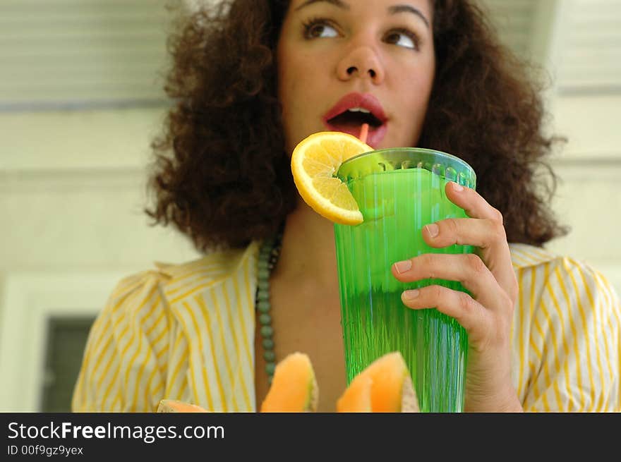 Attractive young woman drinking lemonade on a hot sumer day; seective focus on the hand and the glass