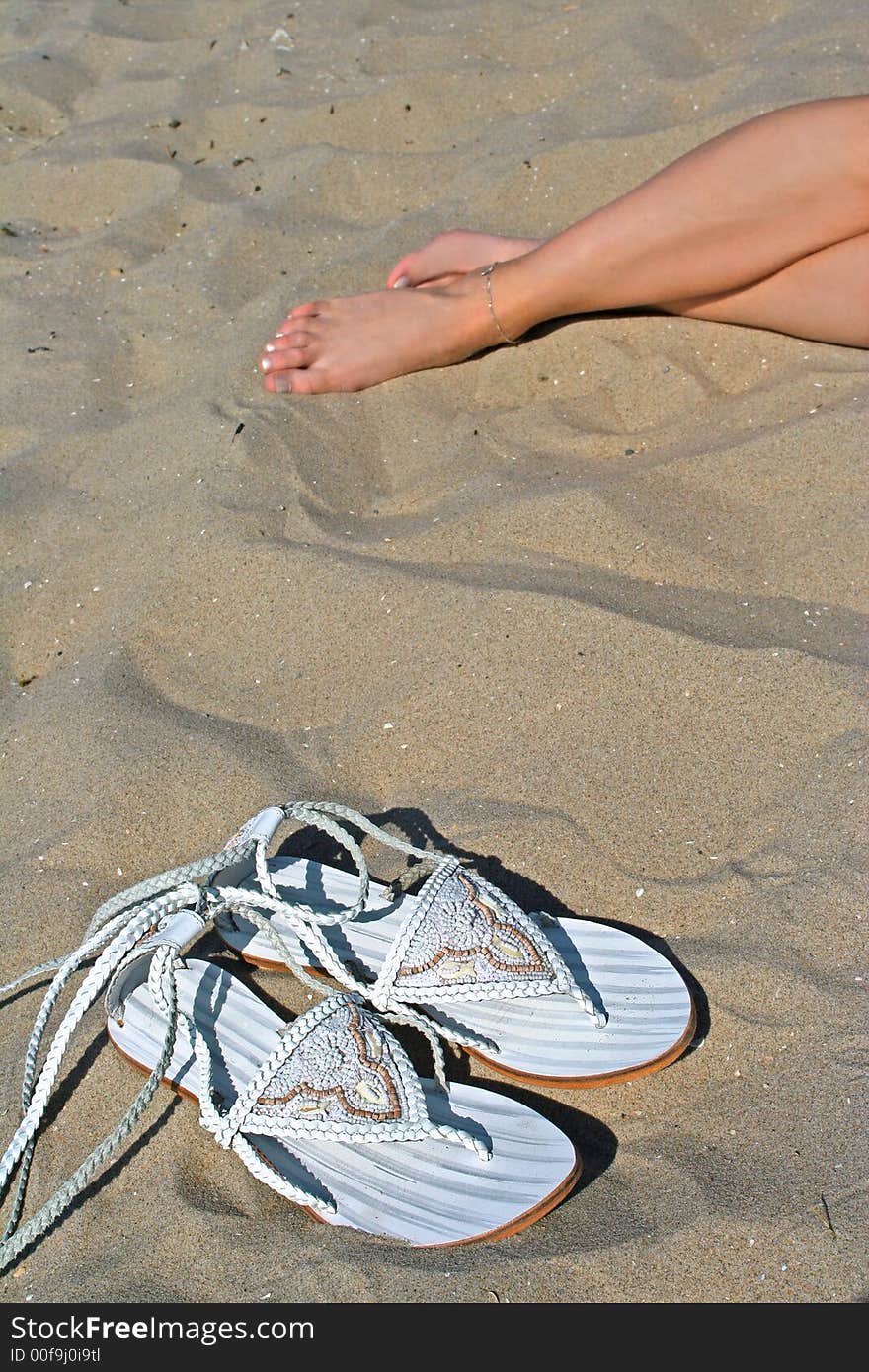 Vacation time on beach with fashion slippers and women legs as background